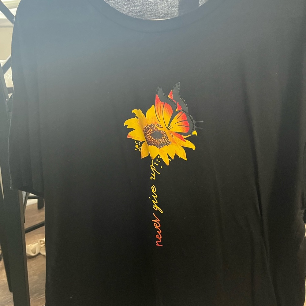 Black short sleeve shirt with “Never give up” leaving the flower